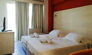 Et hotellrom med to enkeltsenger og en rød vegg bak dem. (AI-generert tekst)