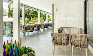 Utemøbler med rottingstoler og bord på en terrasse, med planter og utsikt mot gaten. (AI-generert tekst)