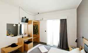 Et hotellrom med en seng, garderobe og et skrivebord. (AI-generert tekst)