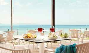 Bilde av et bord dekket på en utendørs restaurant med utsikt over havet. (AI-generert tekst)