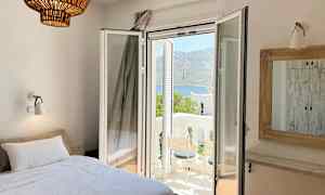 Rom med seng, åpen balkongdør og utsikt over et fjellandskap. (AI-generert tekst)