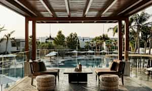 En terrasse med sittemøbler som vender mot et utendørs basseng og palmer. (AI-generert tekst)