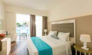 Et hotellrom med en dobbeltseng, nattbord, en stol og et skrivebord. Vinduet har utsikt over et basseng. (AI-generert tekst)