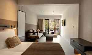 Et hotellrom med seng, sofa og uteplass. (AI-generert tekst)