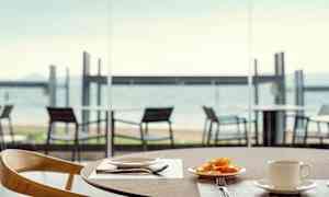 En tallerken med frukt og en kopp på et bord, med utsikt over stranden. (AI-generert tekst)