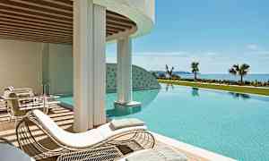 Et utendørs basseng med solsenger og utsikt mot havet. (AI-generert tekst)