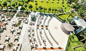 Luftfoto av utendørs sitteområde og grøntområde med trær og parasoller. (AI-generert tekst)