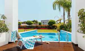 Utendørsbasseng omgitt av grøntområder og solsenger. (AI-generert tekst)