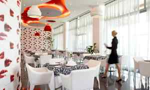 En restaurant med moderne interiør i rødt og hvitt, med dekkede bord og dekorative taklamper. (AI-generert tekst)