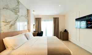 Hotellrom med oppredd seng, vegg-TV og skrivebord nær et vindu. (AI-generert tekst)