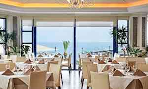 Restaurant med dekkede bord, store vinduer og havutsikt. (AI-generert tekst)