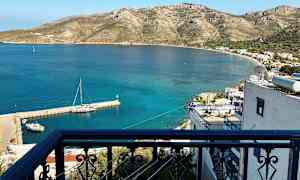 Et balkongrekkverk med utsikt over en liten havn og et kystlandskap med fjell. (AI-generert tekst)