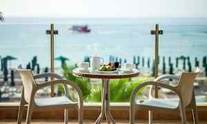 To stoler ved et bord med frukt og drikke, med utsikt over havet. (AI-generert tekst)