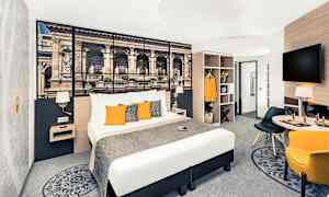 Hotellrom med dobbeltseng, veggdekorasjon, sittegruppe og garderobe. (AI-generert tekst)