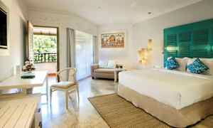 Et lyst hotellrom med en stor seng, en sofa og et skrivebord. Rommet har også en balkong med utsikt mot grøntområde. (AI-generert tekst)