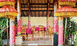 Et innredet rom med tredetaljer, rosa dekorasjoner og bord med stoler. (AI-generert tekst)