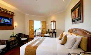 Et hotellrom med en dobbeltseng, skrivebord, sittegruppe og en balkong med utsikt. (AI-generert tekst)