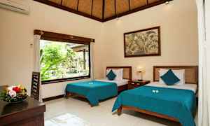 Et lyst og stilrent innredet soverom med to senger med blå sengetepper. Et stort vindu slipper inn naturlig lys og viser grøntområder utenfor. Et fruktfat står på bordet, og et maleri henger på veggen. (AI-generert tekst)