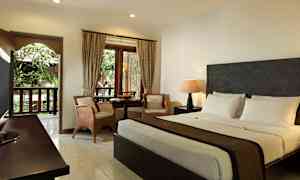 Et hotellrom med dobbeltseng, sittegruppe og vindu med utsikt mot grønne omgivelser. (AI-generert tekst)