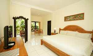 Et velutformet og lyst soverom med en stor seng, tredetaljer og sittegruppe nær vindu med utsikt mot grøntområder. (AI-generert tekst)