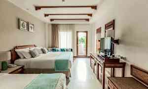 Et hotellrom med to store senger, en TV og et vindu som slipper inn lys og en balkong. (AI-generert tekst)