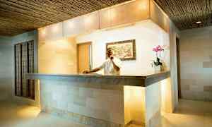 En resepsjonsdisk på et moderne hotell, med et dekorativt maleri på veggen og en blomsterpotte som aksent. (AI-generert tekst)