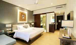 Et soverom med en stor seng, en sittegruppe og et bad i bakgrunnen. (AI-generert tekst)