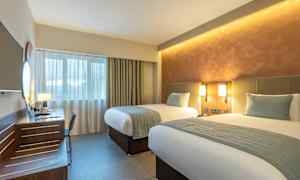 Et hotellrom med to enkeltsenger, skrivebord og vindu. (AI-generert tekst)