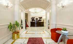 En elegant hotellobby med marmorgulv, en resepsjon i mørkt treverk og en stilig lysekrone. (AI-generert tekst)