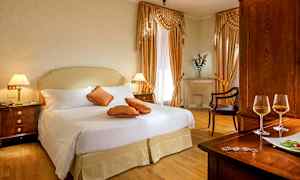 Et elegant hotellrom med dobbeltseng, dekorerte puter og treinteriør. (AI-generert tekst)