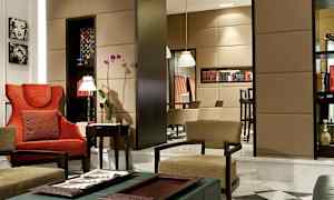 Et elegant innredet stue med røde og beige stoler, blomster og bokhyller. (AI-generert tekst)