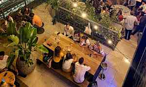 En restaurant med mennesker som sitter ved bord og spiser i en avslappet atmosfære. (AI-generert tekst)