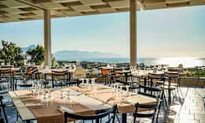 Terrasse med dekkede bord og utsikt over havet. (AI-generert tekst)