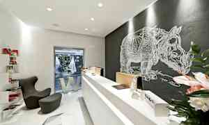 Et moderne kontor med en minimalistisk design, resepsjon og et veggmaleri av en neshorn. (AI-generert tekst)