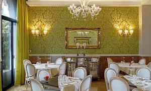 En restaurant med grønne vegger, stilige stoler og bord med duker. (AI-generert tekst)