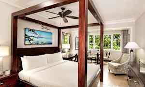 Et hotellrom med en himmelseng, en sittegruppe og et stort vindu. (AI-generert tekst)