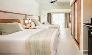 Hotellrom med to senger, lys innredning og store vinduer. (AI-generert tekst)