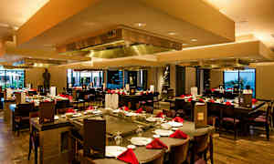 En restaurant med bord dekket med rødservietter og stoler rundt. (AI-generert tekst)