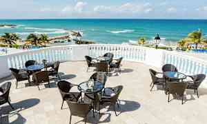 Terrasse med bord og stoler, havutsikt og palmetrær. (AI-generert tekst)