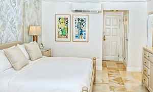 Et lyst og stilrent soverom med en dobbeltseng, veggkunst og en dør. (AI-generert tekst)