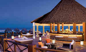 Avslappet lounge og bar med stråtak, ved stranden i skumring. (AI-generert tekst)