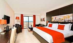 Et hotellrom med seng, sittegruppe og balkongdør. (AI-generert tekst)