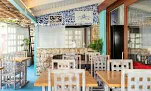 Restaurant med trebord og stoler samt dekorert vegg med blå fliser. (AI-generert tekst)