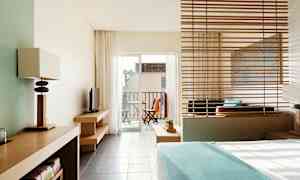 Et hotellrom med moderne interiør og utsikt mot en balkong med utemøbler. (AI-generert tekst)