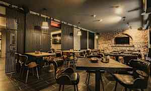 En restaurant med trebord og stoler samt murvegger. (AI-generert tekst)