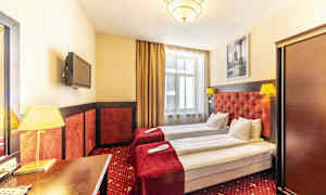 Hotellrom med to enkeltsenger, røde sengetepper og lamper. (AI-generert tekst)