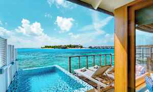 Utsikt fra en terrasse med basseng og solsenger mot havet og en øy med bungalower. (AI-generert tekst)