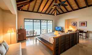 Interiør av et soverom med en dobbeltseng og et åpent vindu mot en balkong. (AI-generert tekst)