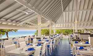 Uterestaurant med hvite møbler og havutsikt. (AI-generert tekst)