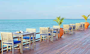 Utendørs servering med bord og stoler ved sjøen. (AI-generert tekst)